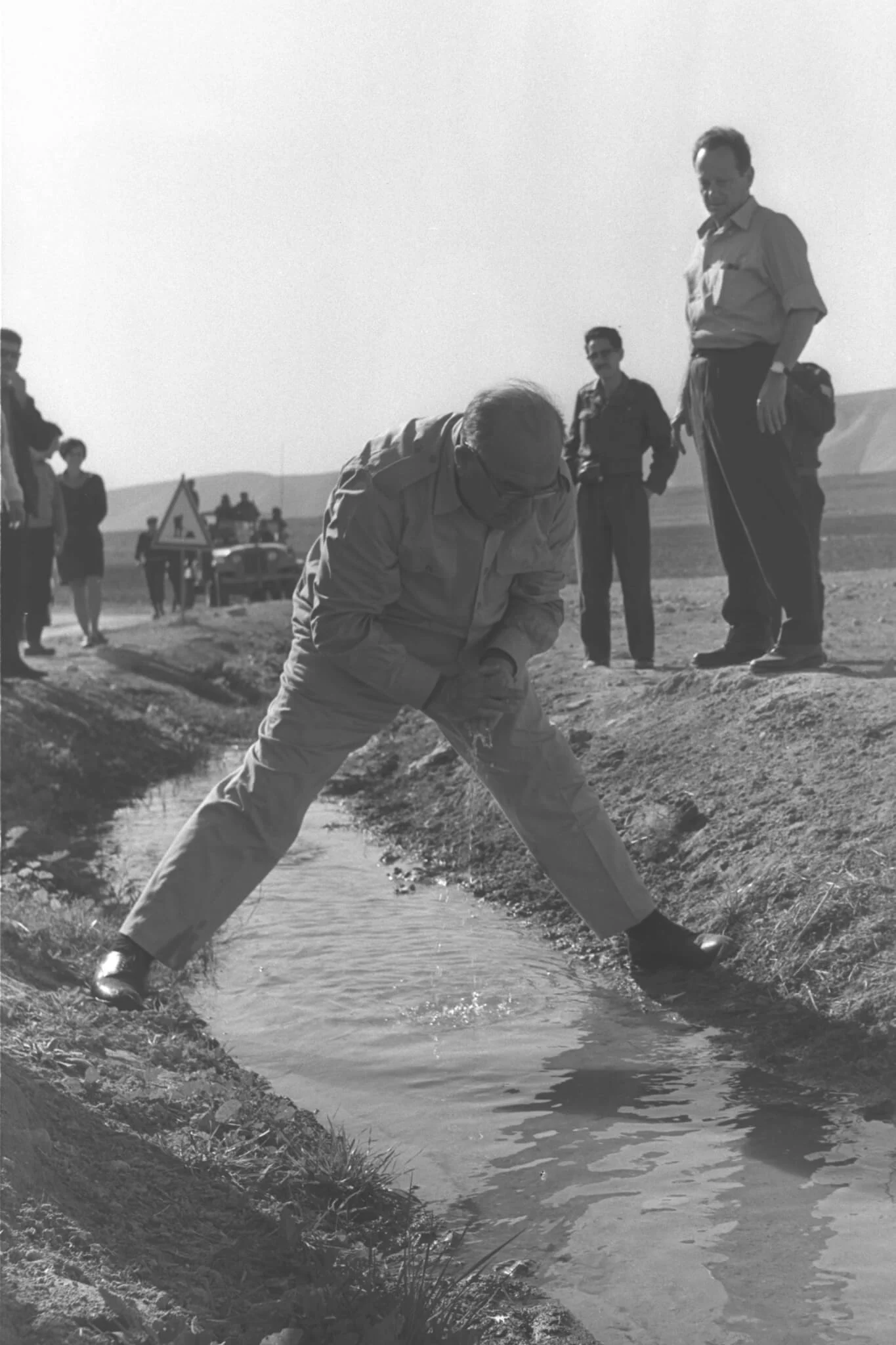 נטוע בשתי הגדות. ראש הממשלה לוי אשכול שותה ממימי מעיין פצאל בעת סיור בבקעת הירדן, דצמבר 1967. מאחוריו השר יגאל אלון. צילום משה מילנר, לע"מ